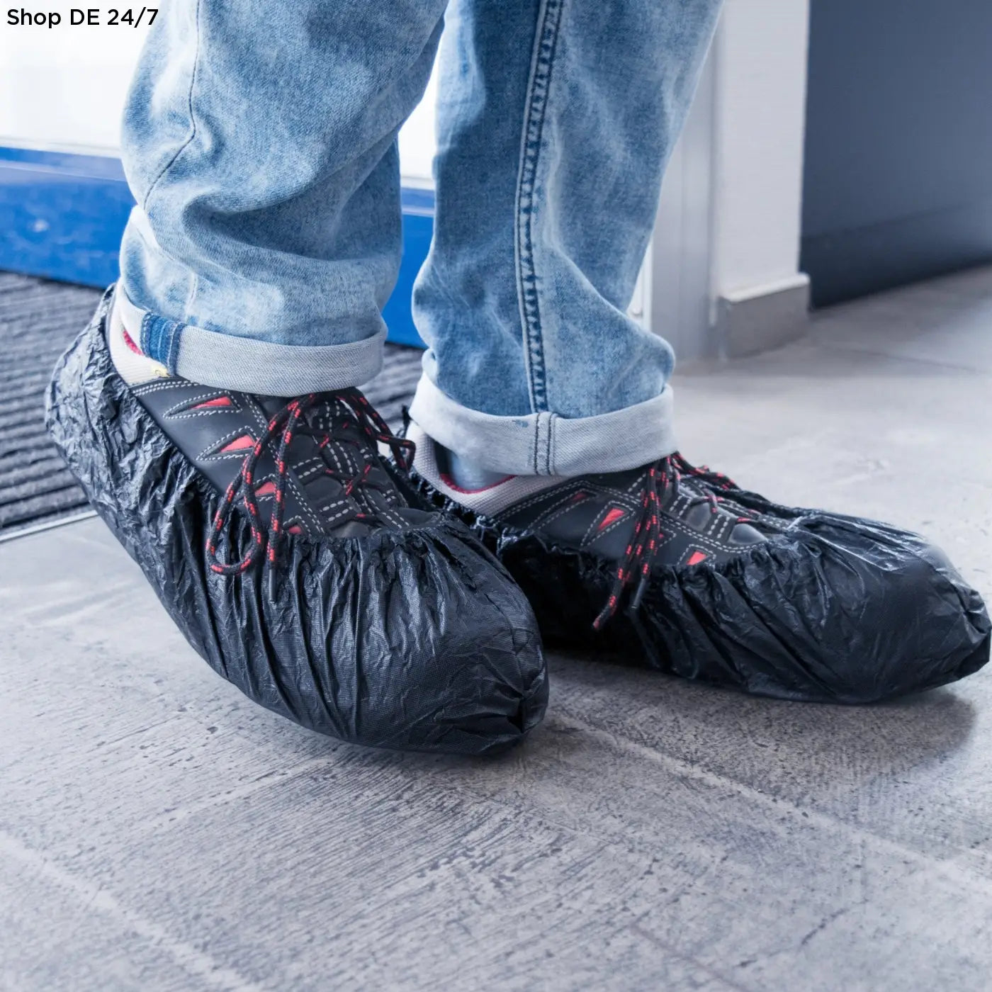 Schwarze cpe-überschuhe in deutscher qualität über dunklen sneakers mit roten schnürsenkeln für zuverlässigen schutz