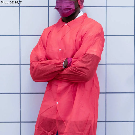 Person trägt nitras pp-besuchermantel in rot mit weißen knöpfen und passenden pinken handschuhen für hygienische und professionelle umgebungen