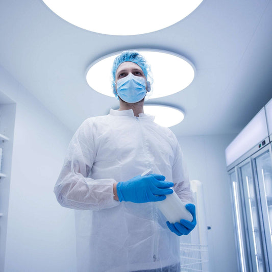 Person in weißem nitras pp-besuchermantel hält durchsichtigen behälter zur sicherstellung hygienischer standards in medizinischen einrichtungen