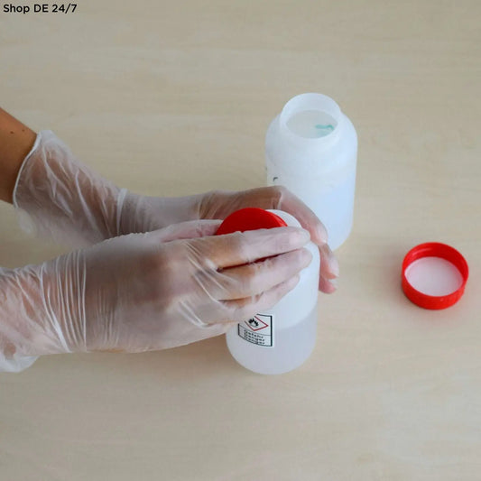 Weiße plastikchemikalienaufbewahrungsflasche mit rotem verschluss und gefahrenhinweis für vinyl pf puderfrei handschuhe