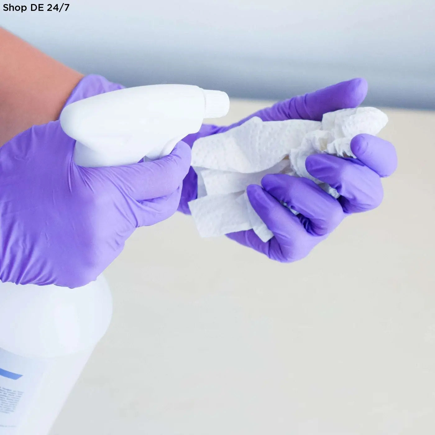 Violet wave nitril-einmalhandschuhe in hochwertiges nitril gehalten, beidseitig tragbar, zeigen eine hand mit sprayflasche und papierhandtüchern