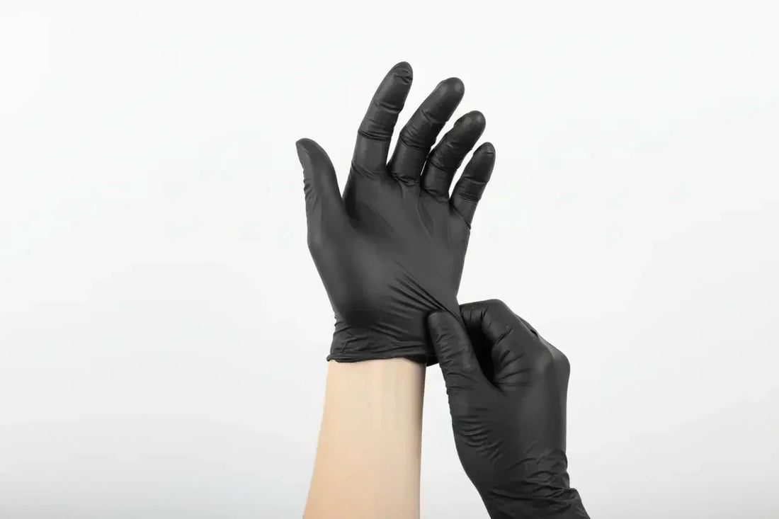 Hand mit schwarzem latexhandschuh als exemplar für einmalhandschuhe in leitfaden zur handschuhpflege und entsorgung