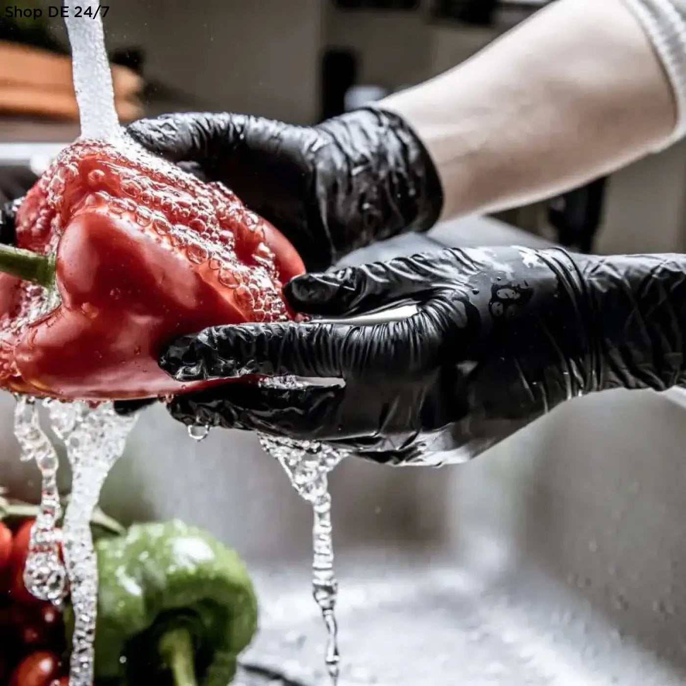 Einmalhandschuhe aus nitril in schwarz werden beim waschen einer roten paprika mit wasser verwendet