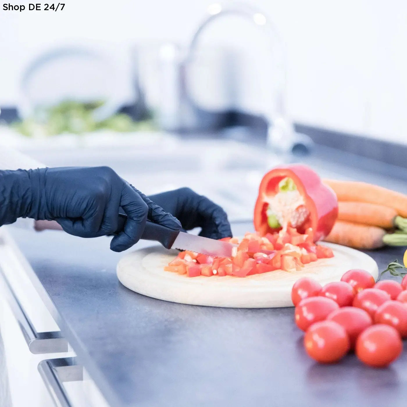 A chef knife with black handle chopping red bell pepper on white board while wearing black wave nitril handschuhe schwarz