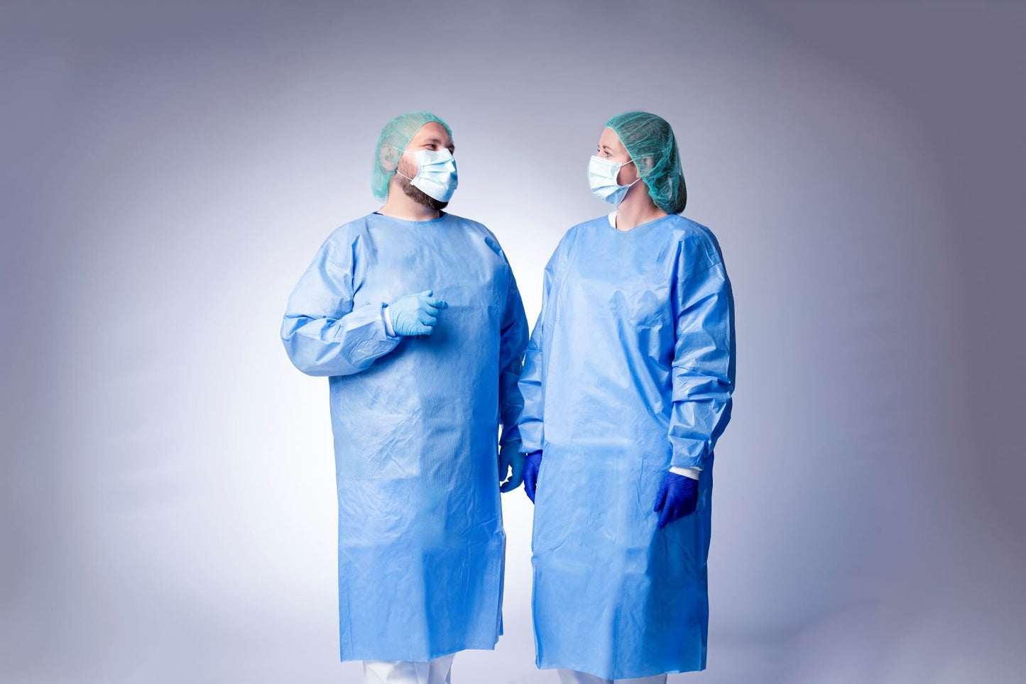 Zwei medizinische fachkräfte tragen blaue chirurgische kleidungen und nitras indigo wave nitril-einmalhandschuhe mit mikrogeraute fingerspitzen für anspruchsvolle umgebungen