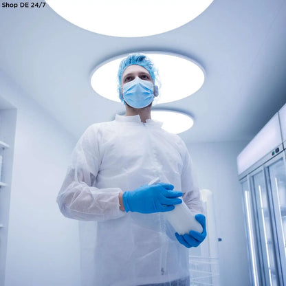 Person in weißem nitras pp-besuchermantel hält durchsichtigen behälter zur sicherstellung hygienischer standards in medizinischen einrichtungen