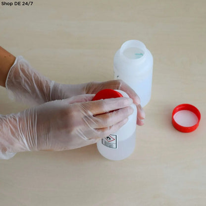 Weiße kunststoff-chemikalienflasche mit rotem deckel und gefahrensymbol für nitras vinyl und vinyl p handschuhe